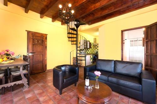 a living room with a black leather couch and a table at Castle Tower apartment PICASSO in rural holiday park in Tolox