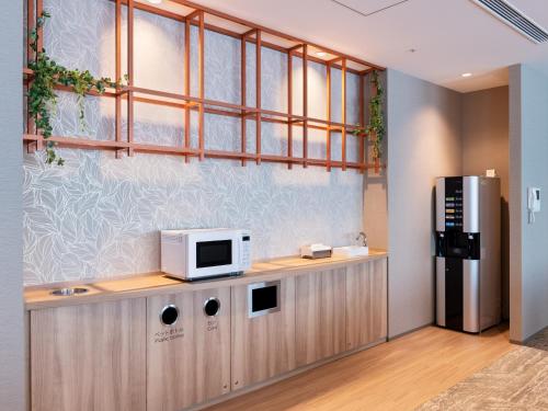 a kitchen with a microwave on top of a counter at Mitsui Garden Hotel Kashiwa-no-ha Park Side - Chiba in Kashiwa