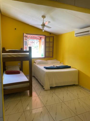 two beds in a room with yellow walls at Pousada Chácara Sonho in Hortolândia