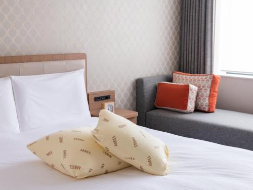 a bedroom with a bed with two pillows and a chair at Mitsui Garden Hotel Kashiwa-no-ha Park Side - Chiba in Kashiwa
