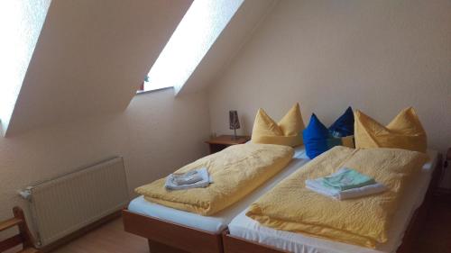 a bedroom with two beds with yellow sheets and blue pillows at Landhaus Mecklenburg in Waren