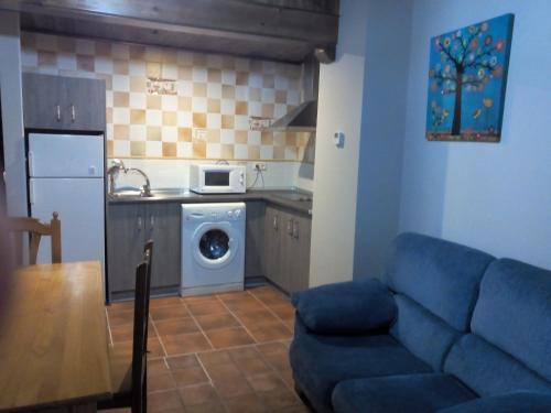 a living room with a blue couch and a kitchen at Casa Rural La Tejada in Alcalá de Moncayo