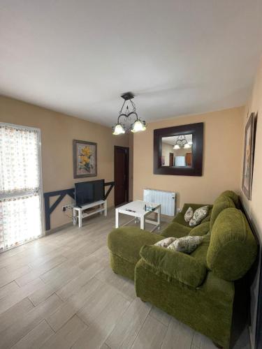 a living room with a green couch and a table at Casa La Peña - Playa y Naturaleza a un paso in La Redondela
