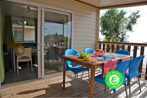 a wooden table and blue chairs on a deck at Campeggio Europa Silvella in San Felice del Benaco