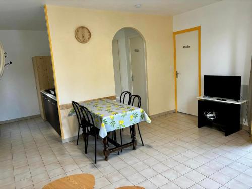 a dining room with a table and chairs and a tv at Hôtel Les Persèdes in Lavilledieu