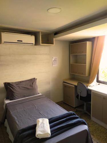 a bedroom with a bed and a desk and a window at MEC Office Hostel in Niterói