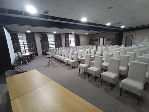 an empty room with rows of chairs and tables at Garnet Hotel & Event Centar in Ruma