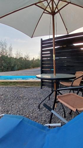 a table and a chair with an umbrella at Grado8punto8 Glamping Valle de Los Artistas in Lolol