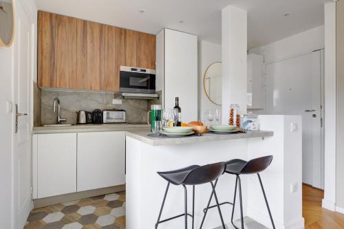 une cuisine avec des armoires blanches et un comptoir avec des tabourets dans l'établissement Bluestay 816 - Superb studio in Paris, à Paris