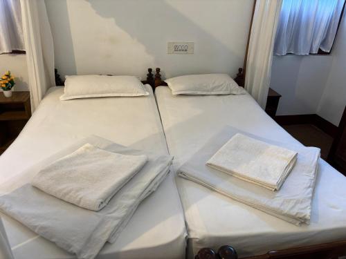 two beds with white sheets and towels on them at Cure Monastery Family Resort in Marayoor