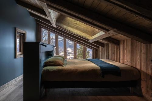 un lit dans une chambre avec une grande fenêtre dans l'établissement Ferme des Choseaux - Grand Confort et ski, à Combloux