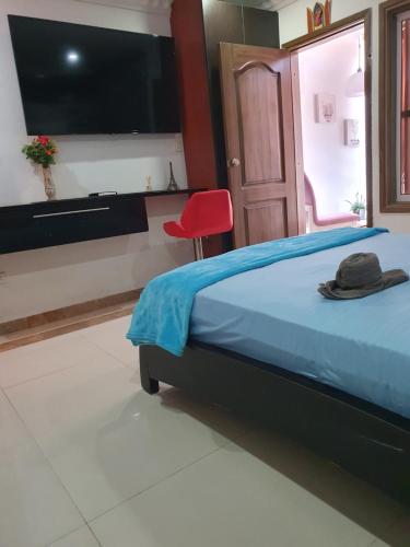 1 dormitorio con 1 cama con TV y silla roja en Hotel Cra17a21a avenida 22 cerca a escenario deportivos iglesias y clinicas, en Santa Marta