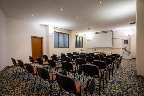 a conference room with chairs and a projection screen at iH Hotels Milano St. John in Sesto San Giovanni