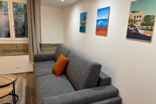- un canapé gris avec un oreiller orange dans le salon dans l'établissement Cosy studio near beach and Museum of Fine Arts, à Nice