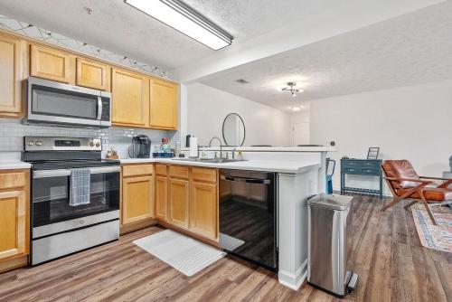 a kitchen with wooden cabinets and a stove top oven at New 4BR 4BA AU Oasis 2 Mins to Downtown & Stadium Sleeps 10 in Auburn
