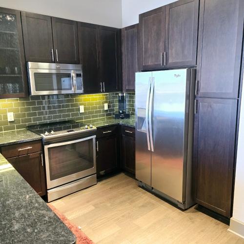 a kitchen with wooden cabinets and a stainless steel refrigerator at Convention Center Downtown Escape in Houston
