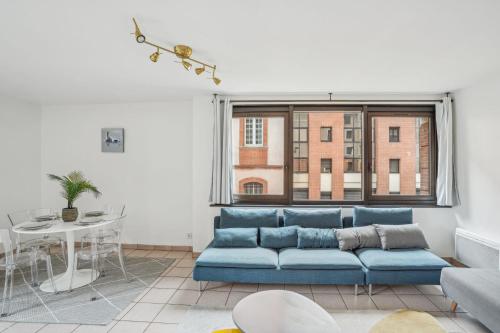 un salon avec un canapé bleu et une fenêtre dans l'établissement Spacieux appartement hyper centre Capitole 3pers wifi, à Toulouse