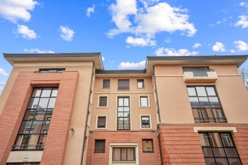 un bâtiment en briques avec des fenêtres et un ciel bleu dans l'établissement Spacieux appartement hyper centre Capitole 3pers wifi, à Toulouse