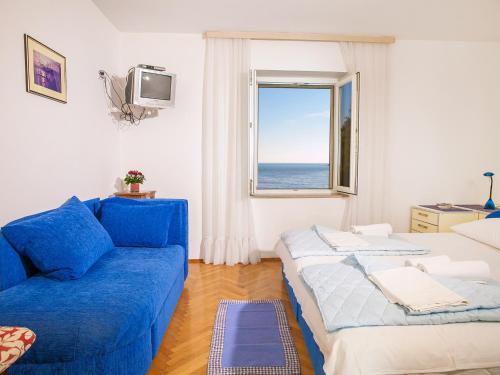 ein Wohnzimmer mit einem blauen Sofa und einem Fenster in der Unterkunft Apartments Adria in Petrovac na Moru