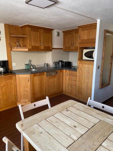 une cuisine avec des armoires en bois et une table en bois dans l'établissement Appartement 6 pers proche des pistes, à Praz-sur-Arly