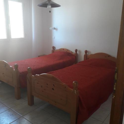 - 2 lits dans une chambre avec des draps rouges et une fenêtre dans l'établissement Residence les Lavandes, à Olmeto