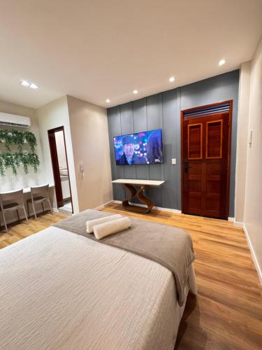a bedroom with a large bed and a flat screen tv at Flat NL in Guarabira