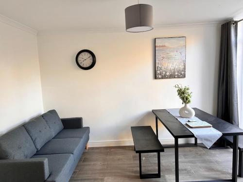 a living room with a couch and a table and a clock at Park Street Accomodation, Room 3 in Luton