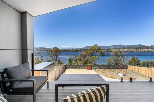 a deck with a table and chairs and a view of the water at Austins Ferry Haven Modern Waterfront Retreat in Austins Ferry
