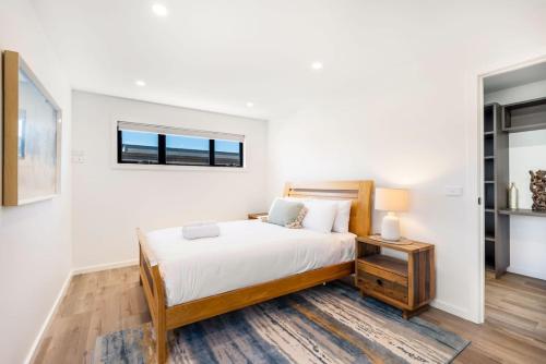a white bedroom with a bed and a window at Austins Ferry Haven Modern Waterfront Retreat in Austins Ferry