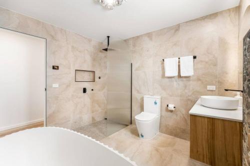 a bathroom with a toilet and a sink and a shower at Austins Ferry Haven Modern Waterfront Retreat in Austins Ferry