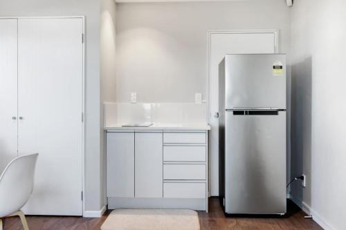 a white kitchen with a refrigerator in a room at The Base Guest Suite with Wi-Fi and Deck in Auckland