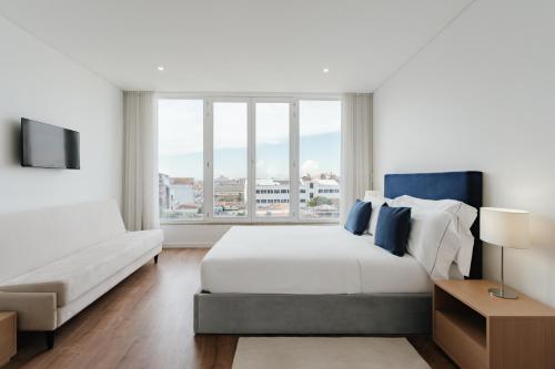 a bedroom with a bed and a couch and a window at Feel Porto Lapa Collection Flats in Porto