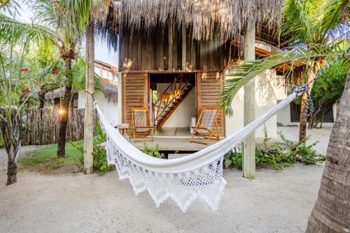 a hammock in front of a beach house at La Cozinha Bungalow in Barra Grande