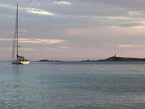 a sailboat in the water with a lighthouse in the background at Villa Acquamarina a 2 passi dal mare in Simius