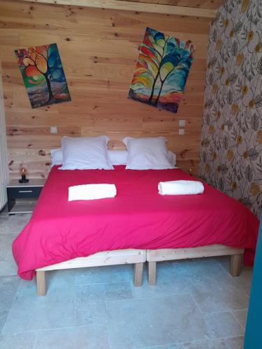 une chambre avec un grand lit rouge avec un mur en bois dans l'établissement Maison de la Truffière, à Bertric-Burée