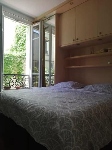 une chambre avec un lit et une grande fenêtre dans l'établissement Apartment near Fort de Montrouge, à Montrouge