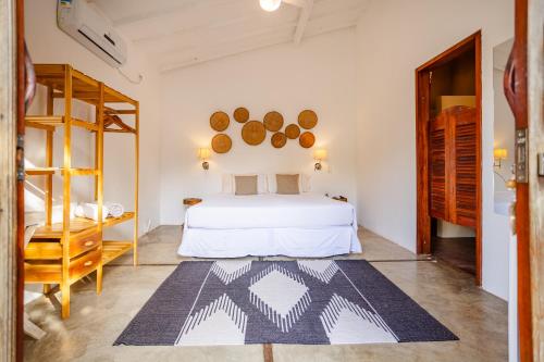 a bedroom with a white bed and a wooden cabinet at La Cozinha Bungalow in Barra Grande