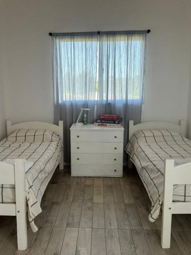 a bedroom with two beds and a dresser and a window at Casaquinta Sunrise La Plata in Abasto