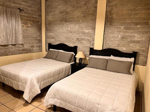 two beds in a bedroom with a brick wall at Hotel Terracota in San Miguel de Allende