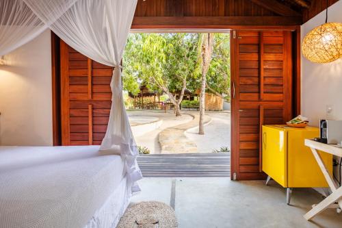 a bedroom with a bed and a sliding glass door at La Cozinha Bungalow in Barra Grande