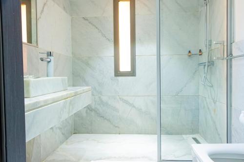 a bathroom with a glass shower and a sink at Atelier Loft Oliver Palm Resort in Marrakesh