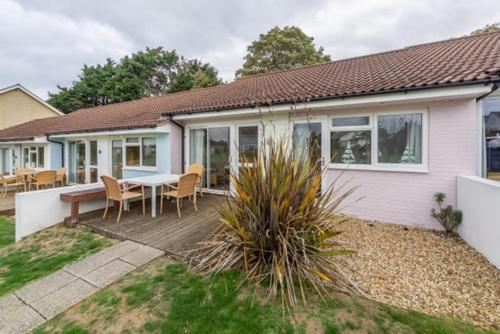 a house with a table and chairs on a deck at Cape A2 Westbay Club, a 2 bedroom cottage, Isle of Wight in Yarmouth