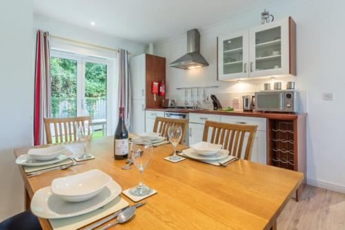 a kitchen with a wooden table with plates and wine glasses at Cape A2 Westbay Club, a 2 bedroom cottage, Isle of Wight in Yarmouth