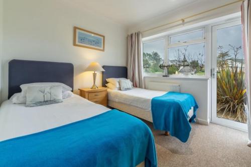 a bedroom with two beds and a large window at Cape A2 Westbay Club, a 2 bedroom cottage, Isle of Wight in Yarmouth