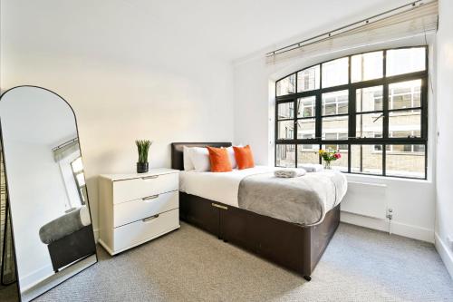 a bedroom with a large bed and a mirror at Farringdon Comfortable 2 Bed Apartments in London