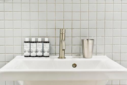 a white sink in a bathroom with white tiles at Farringdon Comfortable 2 Bed Apartments in London