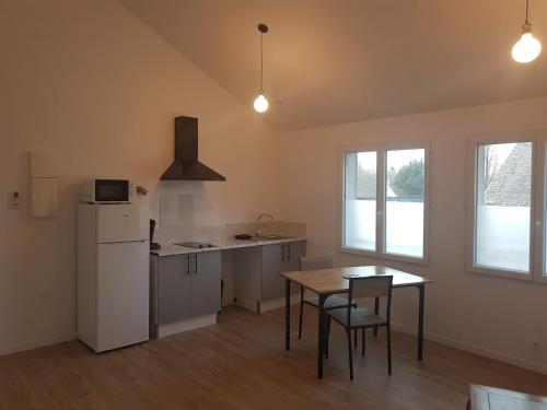a kitchen with a table and a white refrigerator at Sublime maison en pierre 12 pers in Miniac-Morvan