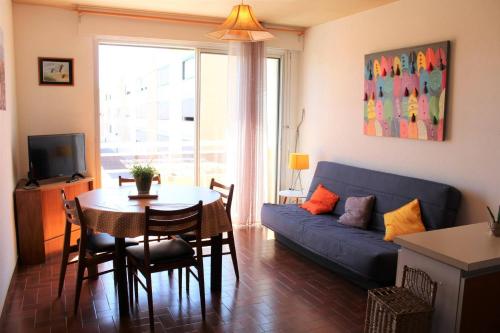 un salon avec une table et un canapé bleu dans l'établissement Appartement 3 pièces PORT LA NOUVELLE PN050-015, à Port-la-Nouvelle