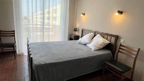 - un lit dans une chambre avec une fenêtre et une chaise dans l'établissement Appartement 3 pièces PORT LA NOUVELLE PN050-015, à Port-la-Nouvelle
