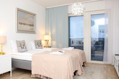a white bedroom with a bed and a window at Arctic Holiday Suite in Rovaniemi